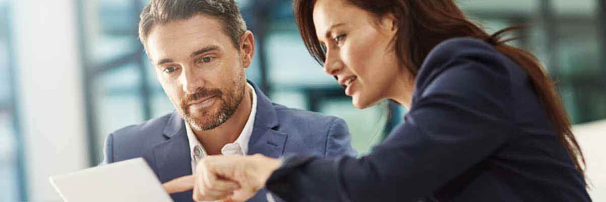 Frau und Mann in Businessanzügen besprechen etwas auf ihrem Tablet