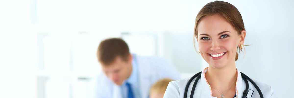 Ärztin in medizinischer Berufskleidung steht in einem Krankenhausflur.