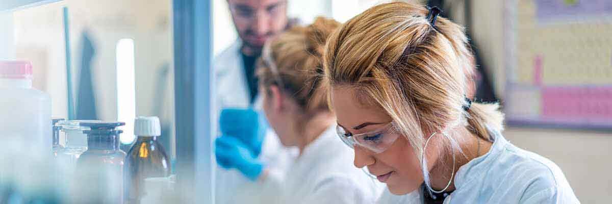 Junge Wissenschaftlerin analysiert Proben unter einem Mikroskop in einem biologischen Forschungslabor.