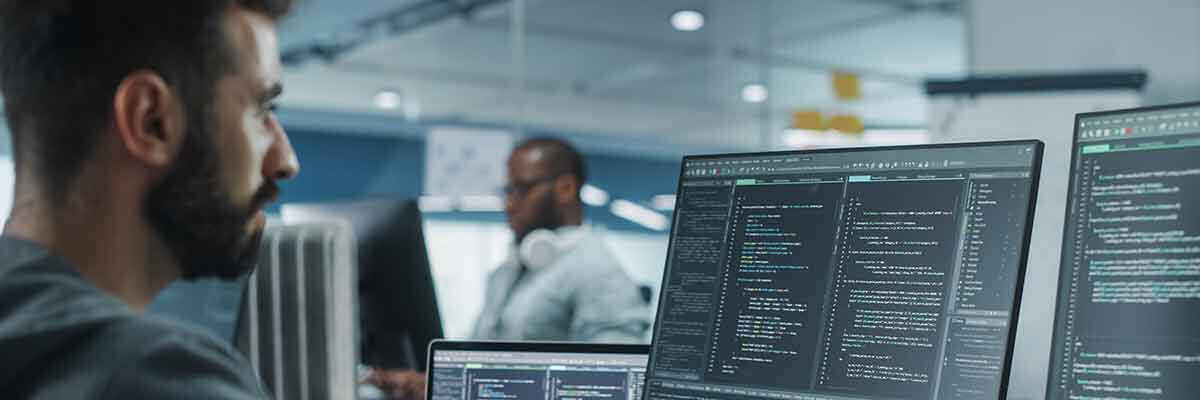 Begeisterter IT-Programmierer arbeitet an einem Desktop-Computer in einem modernen Büro.