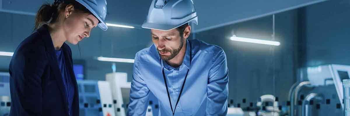 Frau leitet ein Meeting in einem modernen Industriebüro mit Kollegen um einen digitalen Bildschirm.