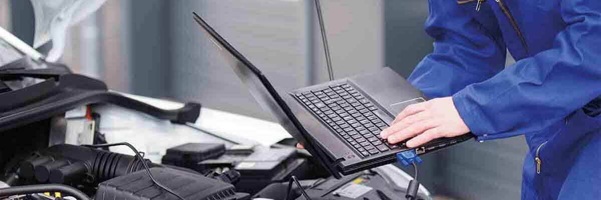 Kfz-Mechatroniker arbeitet an einem Automotor in einer Werkstatt.