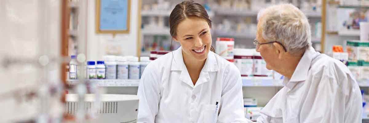 Apothekerin erklärt einem Kunden Medikamenteninformationen in einer modernen Apotheke.