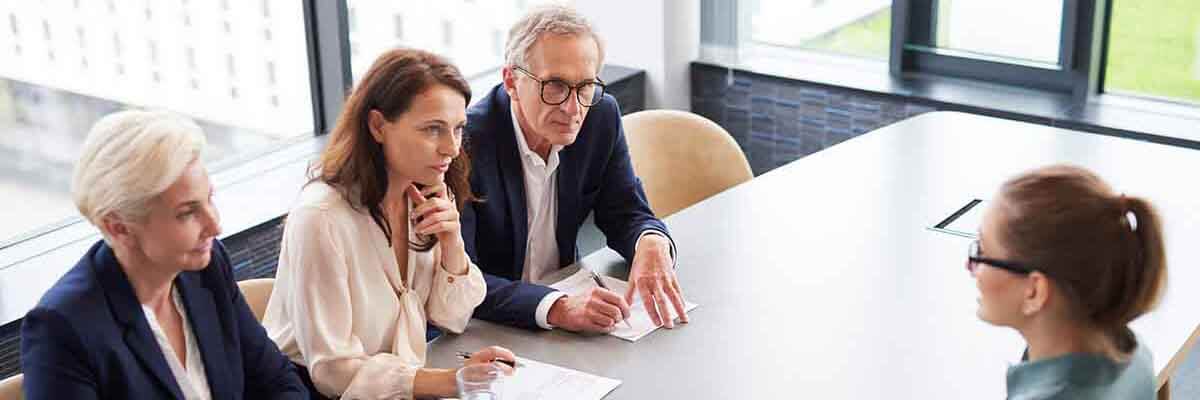 Frau während eines Vorstellungsgesprächs mit drei elegant gekleideten Mitgliedern des Managementteams.